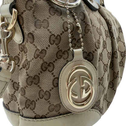 https://cdn.shopify.com/s/files/1/0564/9376/8855/files/Gucci_Handtasche_Sukey_mit_Umhangegurt_monogram_beige_vintage_GG7938.webp?v=1779966403