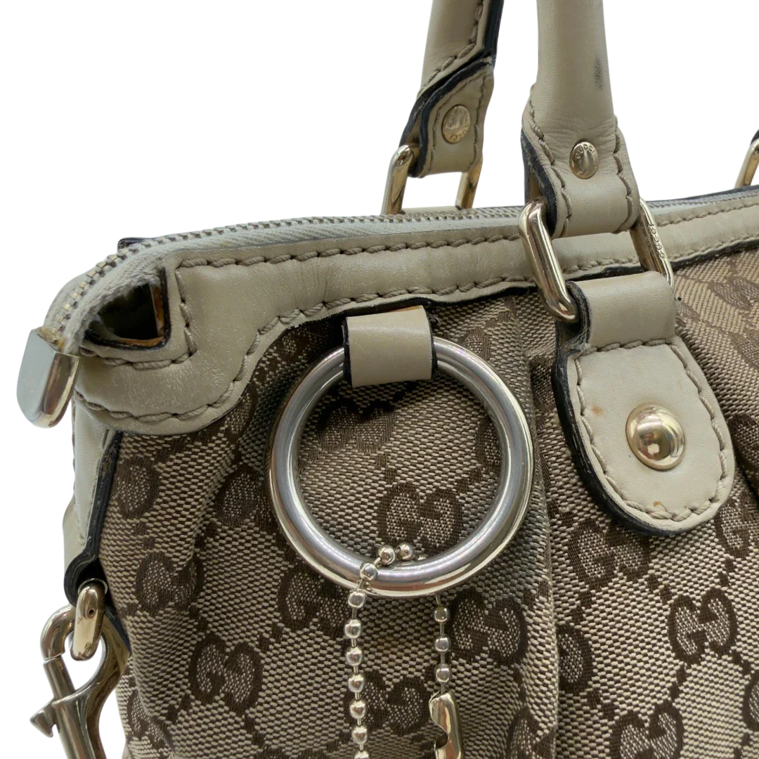 https://cdn.shopify.com/s/files/1/0564/9376/8855/files/Gucci_Handtasche_Sukey_mit_Umhangegurt_monogram_beige_vintage_GG7939.webp?v=1779966403