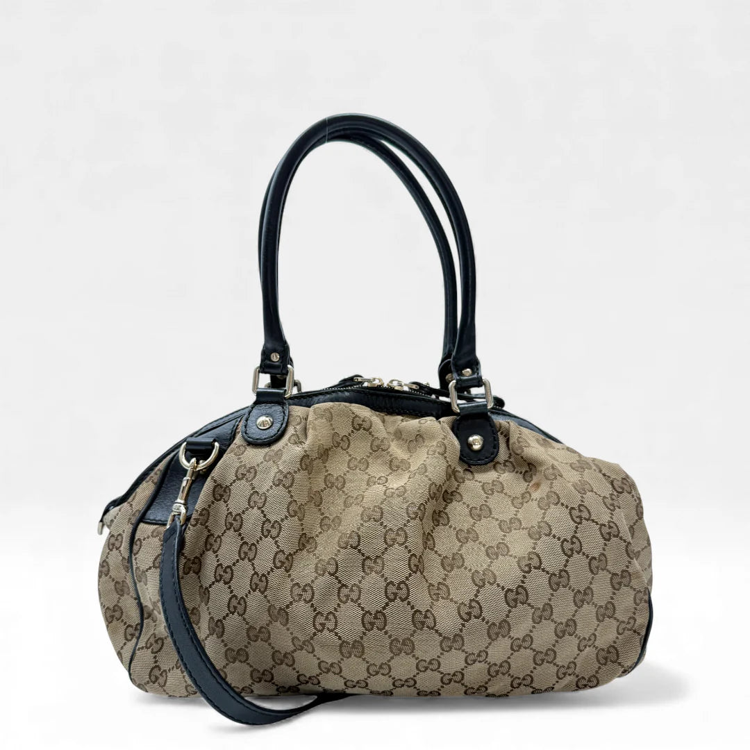 https://cdn.shopify.com/s/files/1/0564/9376/8855/files/Gucci_Handtasche_Sukey_mit_Umhangegurt_monogram_beige_vintage_GG_handbag4614.webp?v=1764897302