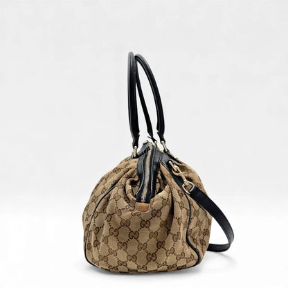 https://cdn.shopify.com/s/files/1/0564/9376/8855/files/Gucci_Handtasche_Sukey_mit_Umhangegurt_monogram_beige_vintage_GG_handbag4618.webp?v=1764897302