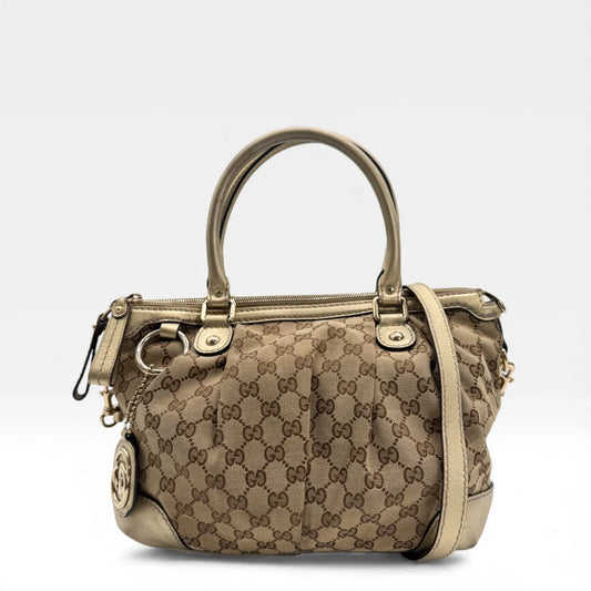 https://cdn.shopify.com/s/files/1/0564/9376/8855/files/Gucci_Handtasche_Sukey_mit_Umhangegurt_monogram_beige_vintage_GG_handbag_4636.webp?v=1765401981