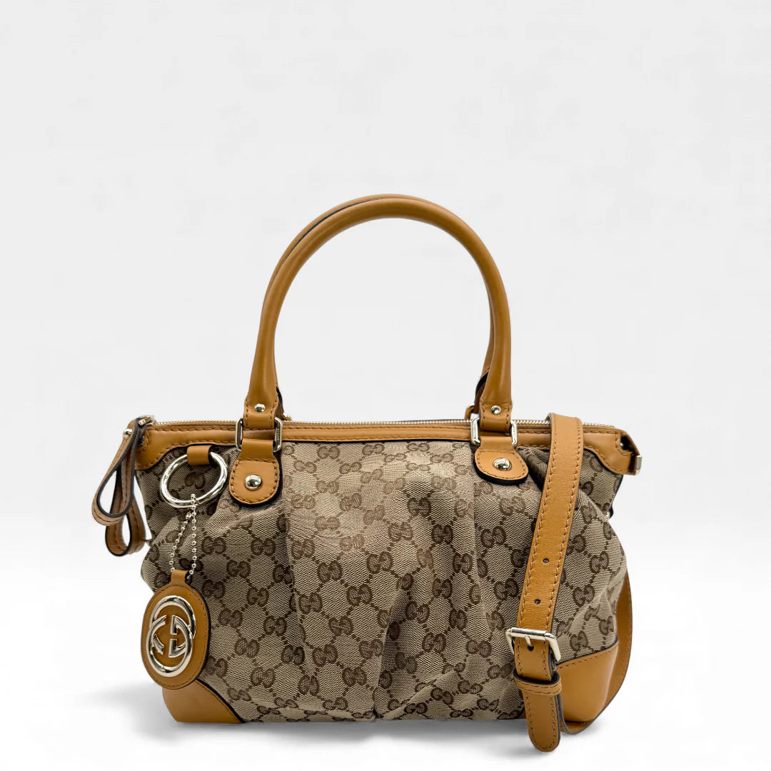 https://cdn.shopify.com/s/files/1/0564/9376/8855/files/Gucci_Handtasche_Sukey_mit_Umhangegurt_monogram_beige_vintage_GG_handbag_5035.webp?v=1765385303