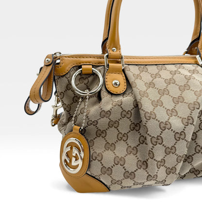 https://cdn.shopify.com/s/files/1/0564/9376/8855/files/Gucci_Handtasche_Sukey_mit_Umhangegurt_monogram_beige_vintage_GG_handbag_5046.webp?v=1765385313