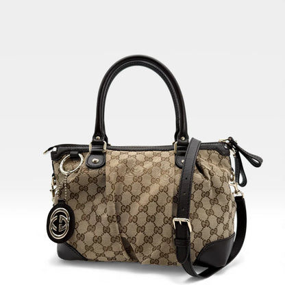 https://cdn.shopify.com/s/files/1/0564/9376/8855/files/Gucci_Handtasche_Sukey_mit_Umhangegurt_monogram_beige_vintage_GG_handbag_5056.webp?v=1765383752