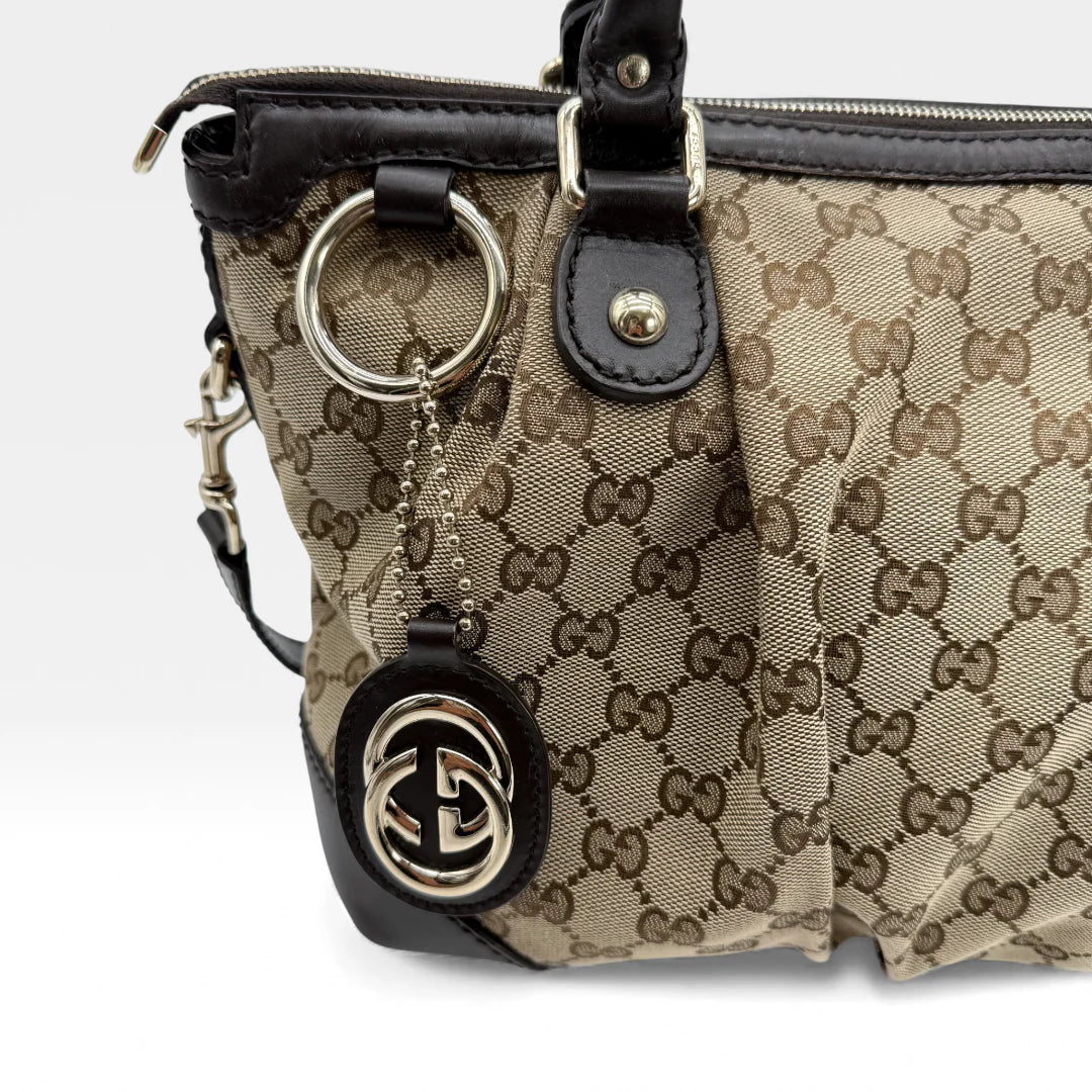https://cdn.shopify.com/s/files/1/0564/9376/8855/files/Gucci_Handtasche_Sukey_mit_Umhangegurt_monogram_beige_vintage_GG_handbag_5070.webp?v=1765383774