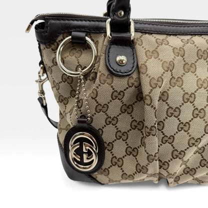 https://cdn.shopify.com/s/files/1/0564/9376/8855/files/Gucci_Handtasche_Sukey_mit_Umhangegurt_monogram_beige_vintage_GG_handbag_5070.webp?v=1765383774