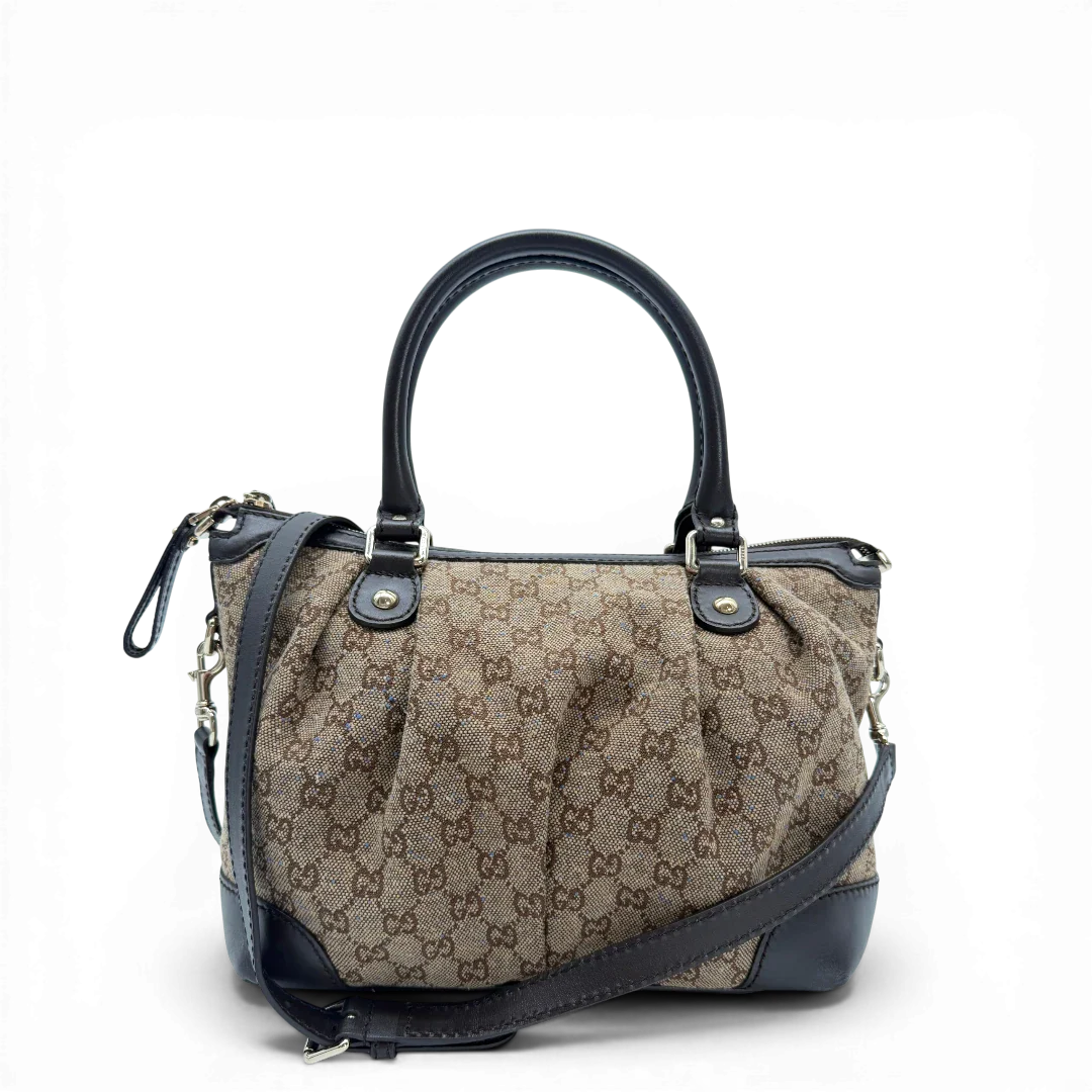 https://cdn.shopify.com/s/files/1/0564/9376/8855/files/Gucci_Handtasche_Sukey_mit_Umhangegurt_monogram_braun_vintage_GG6156.webp?v=1775064878