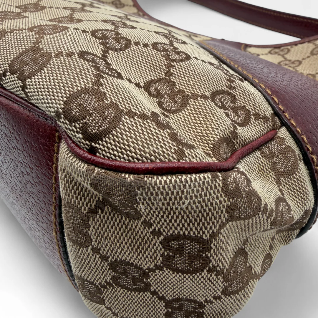 https://cdn.shopify.com/s/files/1/0564/9376/8855/files/Gucci_Handtasche_dunkelrote_Lederdetails_monogram_beige_vintage_GG_handbag7155.webp?v=1758890793