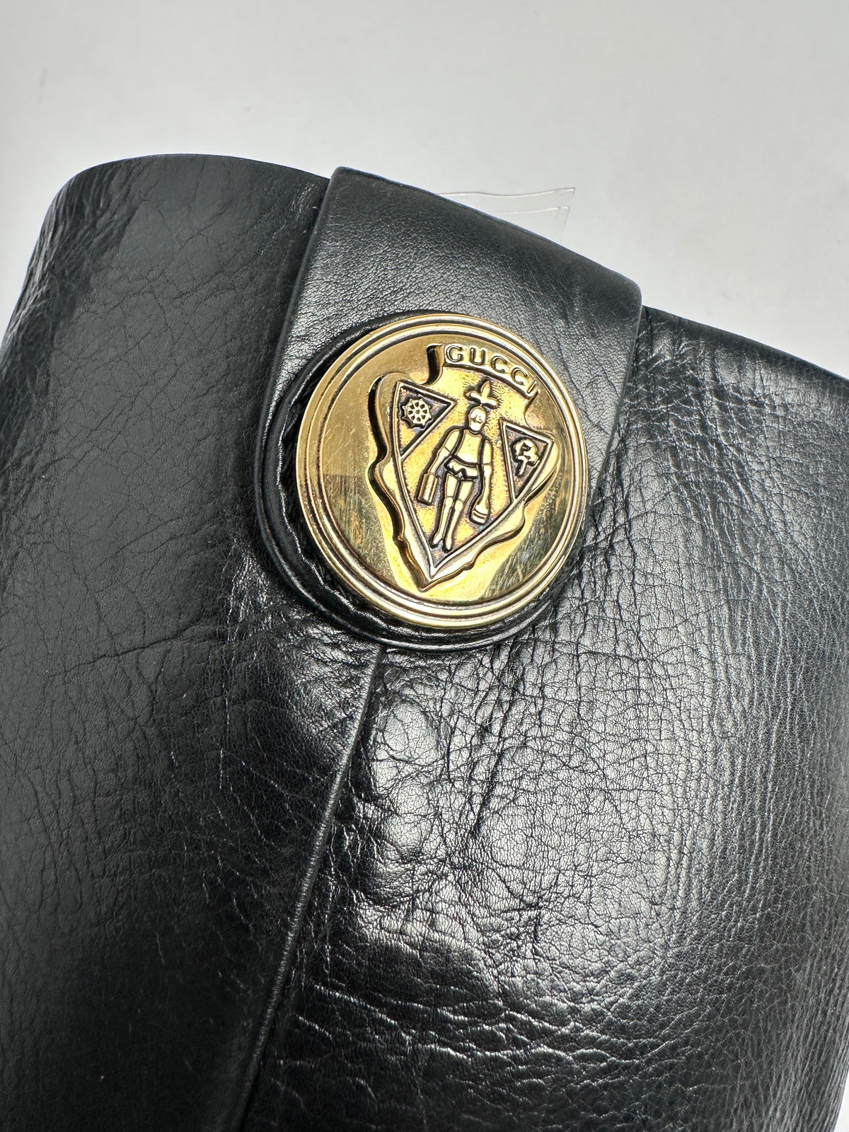 Black leather wallet with a gold emblem on a light gray background