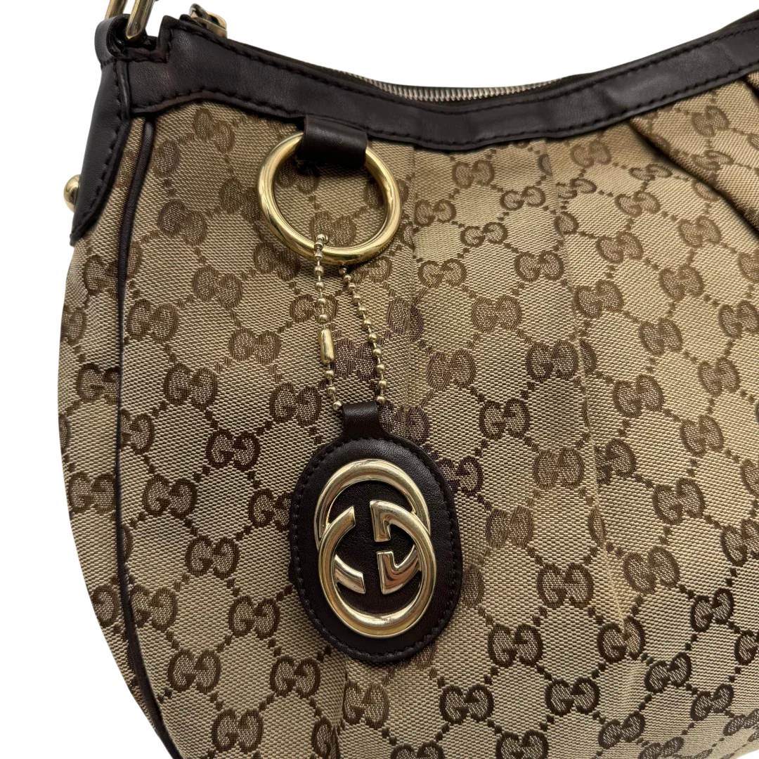 https://cdn.shopify.com/s/files/1/0564/9376/8855/files/Gucci_Umhangetasche_Sukey_One_monogram_beige_vintage_GG2138.webp?v=1779963480