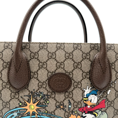 https://cdn.shopify.com/s/files/1/0564/9376/8855/files/Gucci_x_Disney_Handtasche___Tote_Bag_Donald_Duck_Ebony_GG_Supreme_monogram_beige___braun4317.webp?v=1764850487