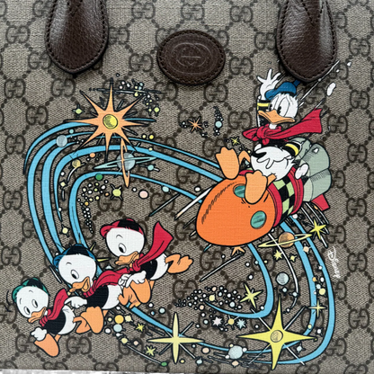 https://cdn.shopify.com/s/files/1/0564/9376/8855/files/Gucci_x_Disney_Handtasche___Tote_Bag_Donald_Duck_Ebony_GG_Supreme_monogram_beige___braun4318.webp?v=1764850487