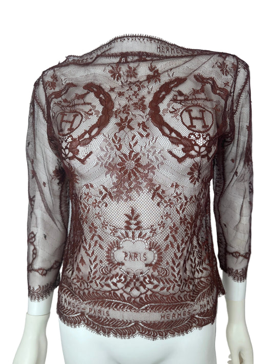 A sheer brown lace shawl with ornate floral and scroll patterns, draped over a white mannequin torso against a plain white background.