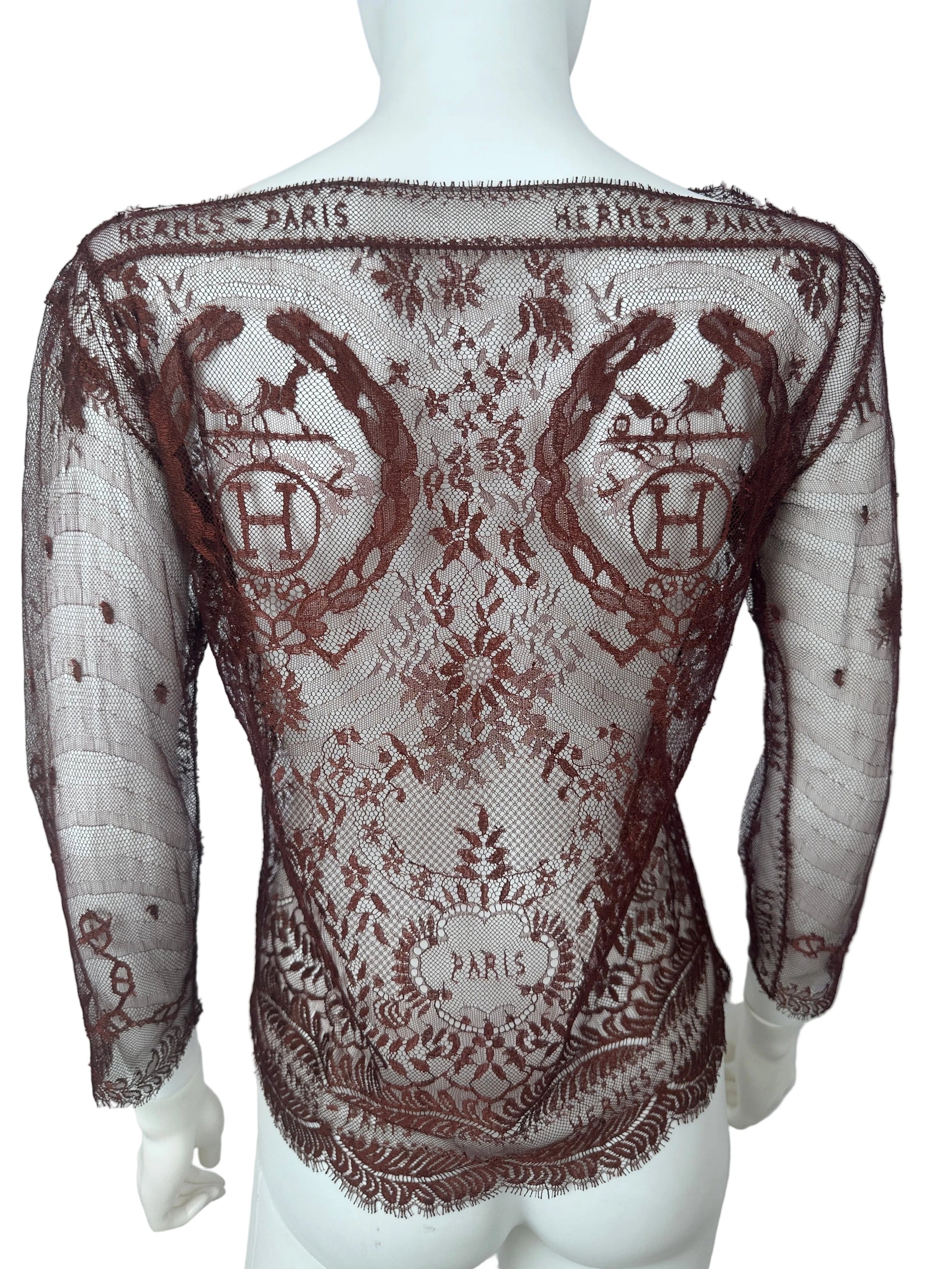A sheer brown lace shawl with embroidered monogram patterns and floral motifs, draped over a white mannequin torso.
