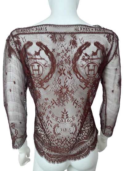 A sheer brown lace shawl with embroidered monogram patterns and floral motifs, draped over a white mannequin torso.
