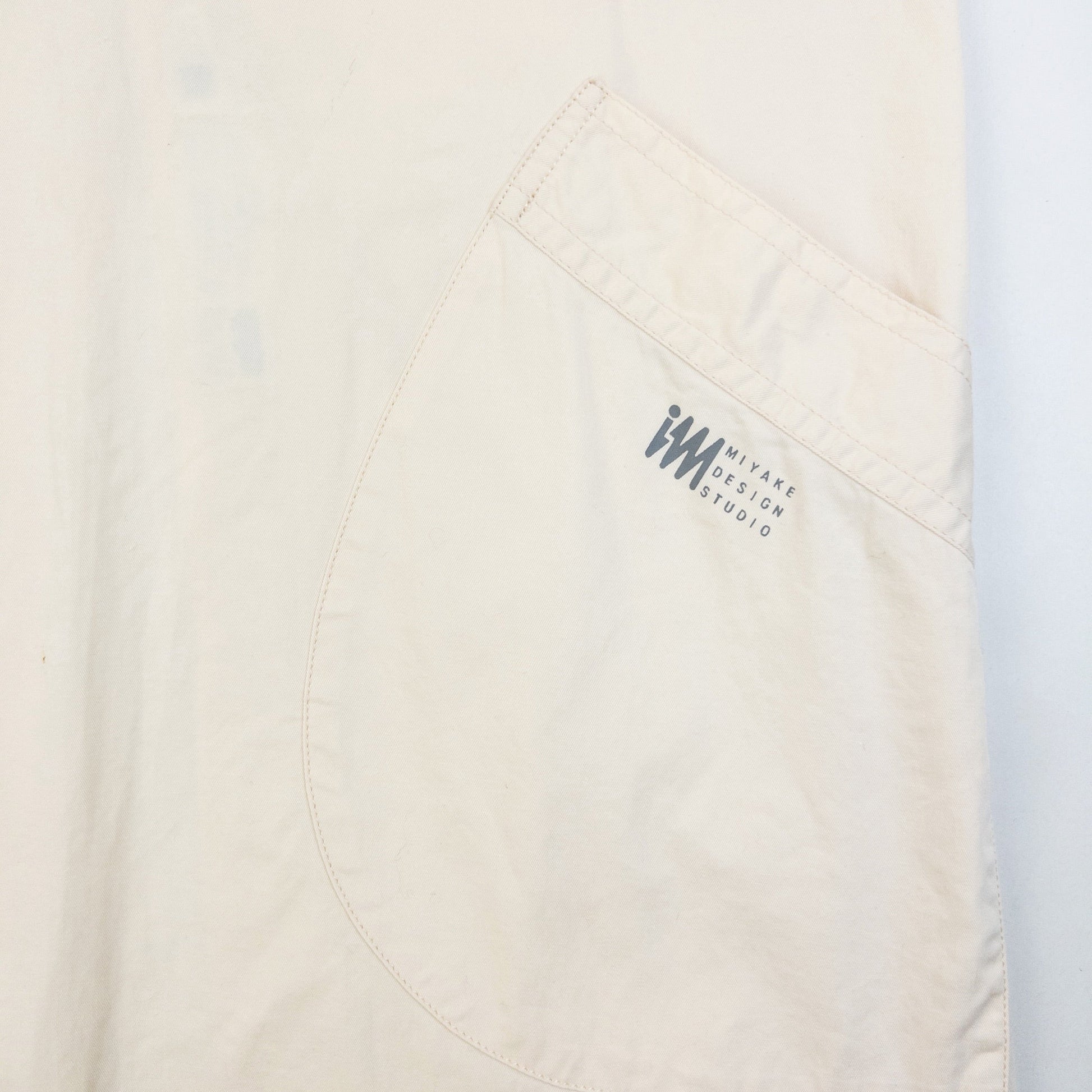 ISSEY MIYAKE beige apron with crossed back straps and stamped logo pocket detail