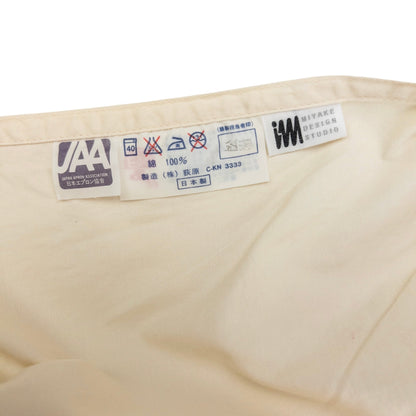 ISSEY MIYAKE beige apron with crossed back straps and stamped logo pocket detail