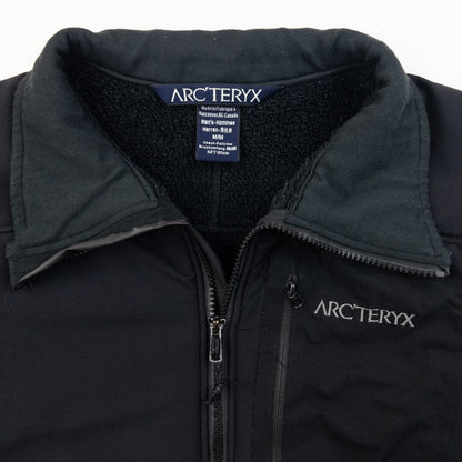 ARCTERYX black fleece jacket with embroidered logo on chest and zippered pockets.