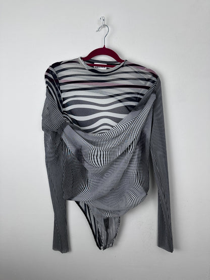 A long-sleeve striped knit top with black, white, and gray wavy patterns, draped on a red hanger against a plain light gray background.