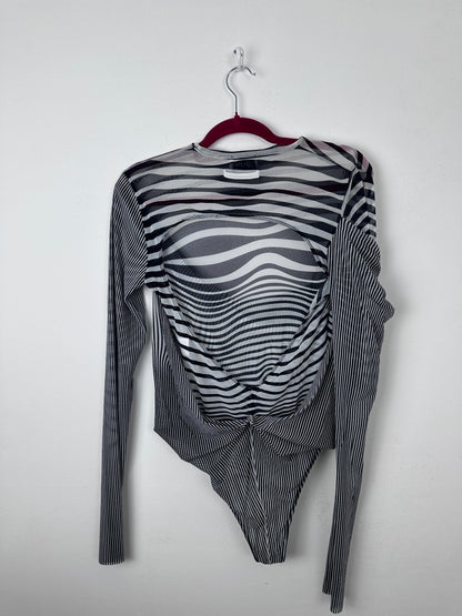 A long-sleeve sheer mesh top with a black and white wavy stripe pattern, laid flat on a white background with a red hanger.