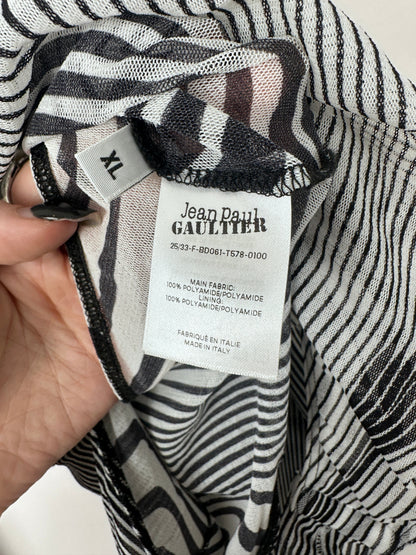Close-up of a black and white striped fabric garment showing the interior label which reads Jean Pataud, alongside a hand holding the fabric open.