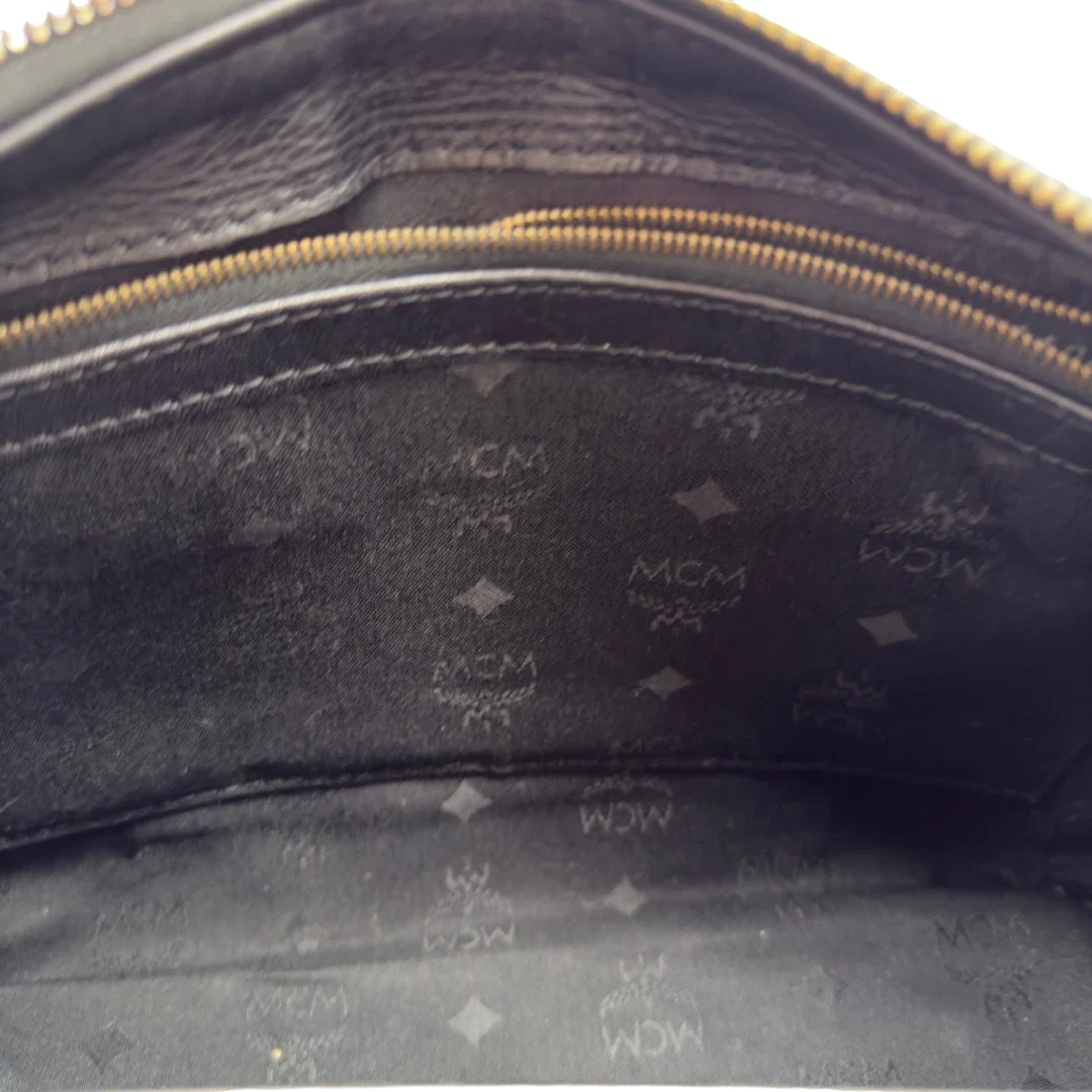 https://cdn.shopify.com/s/files/1/0564/9376/8855/files/MCM_Handtasche_Boston_25_PVC_mit_Umhangegurt_schwarz_20.webp?v=1782983949