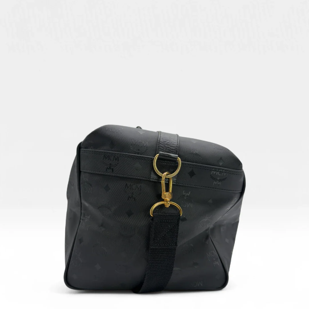 https://cdn.shopify.com/s/files/1/0564/9376/8855/files/MCM_Reisetasche_50_PVC_mit_Umhangegurt_monogram_schwarz_Vintage_luxury_MCM_Dufflebag4970.webp?v=1754500863