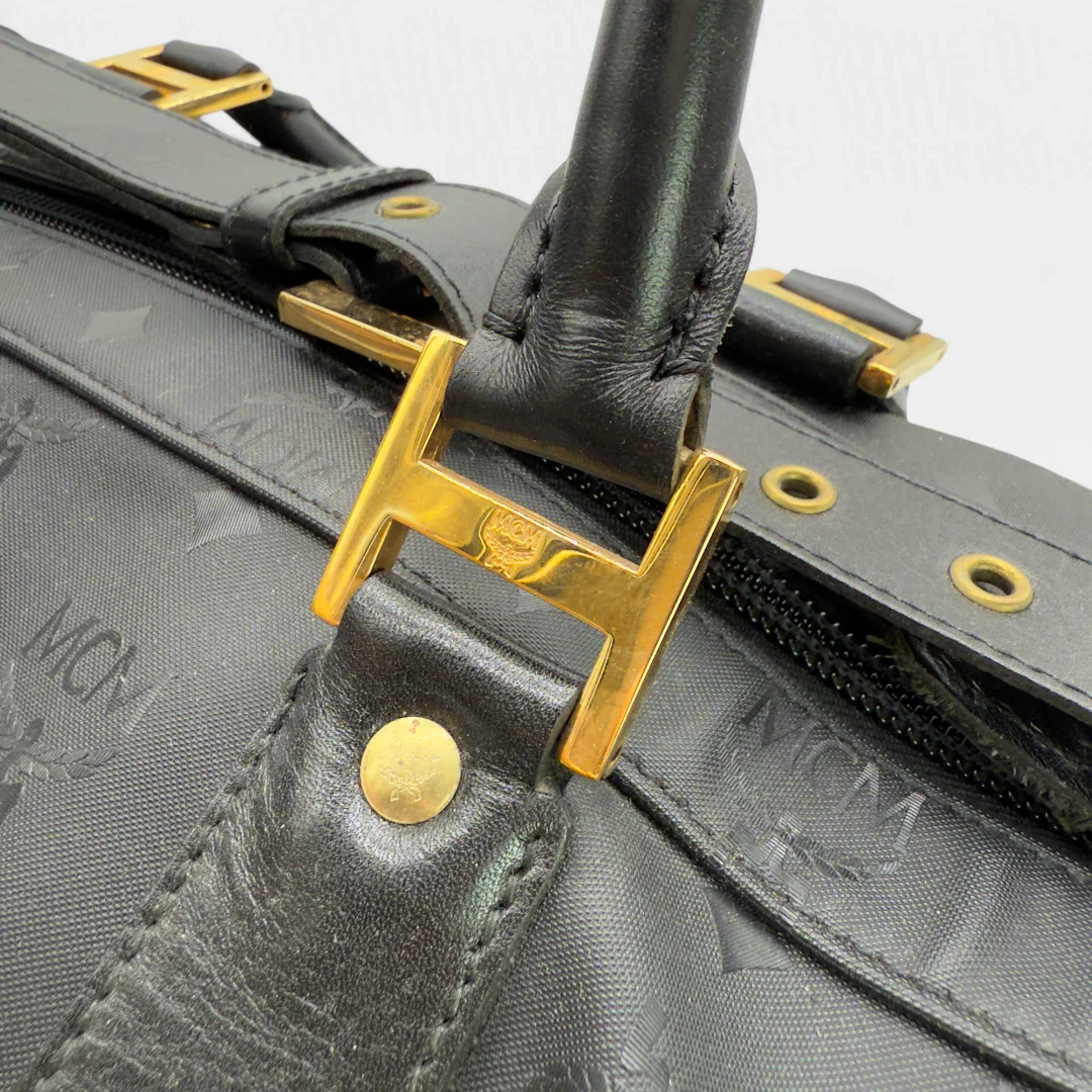 https://cdn.shopify.com/s/files/1/0564/9376/8855/files/MCM_Reisetasche_50_PVC_mit_Umhangegurt_monogram_schwarz_Vintage_luxury_MCM_Dufflebag4977.webp?v=1754669422
