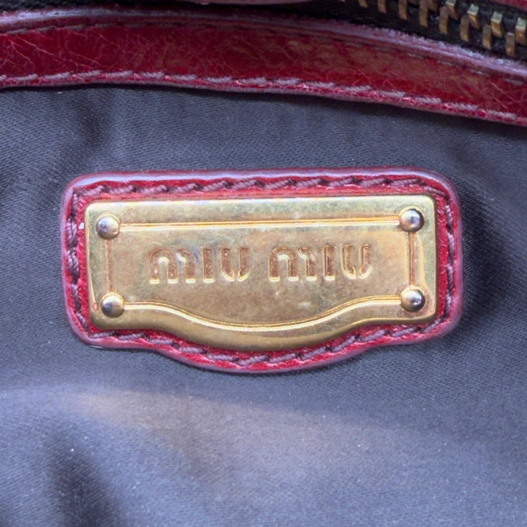 https://cdn.shopify.com/s/files/1/0564/9376/8855/files/Miu_Miu_Handtasche_Vitello_Lux_aus_Leder_dunkelrot_vintage7270.webp?v=1778681884