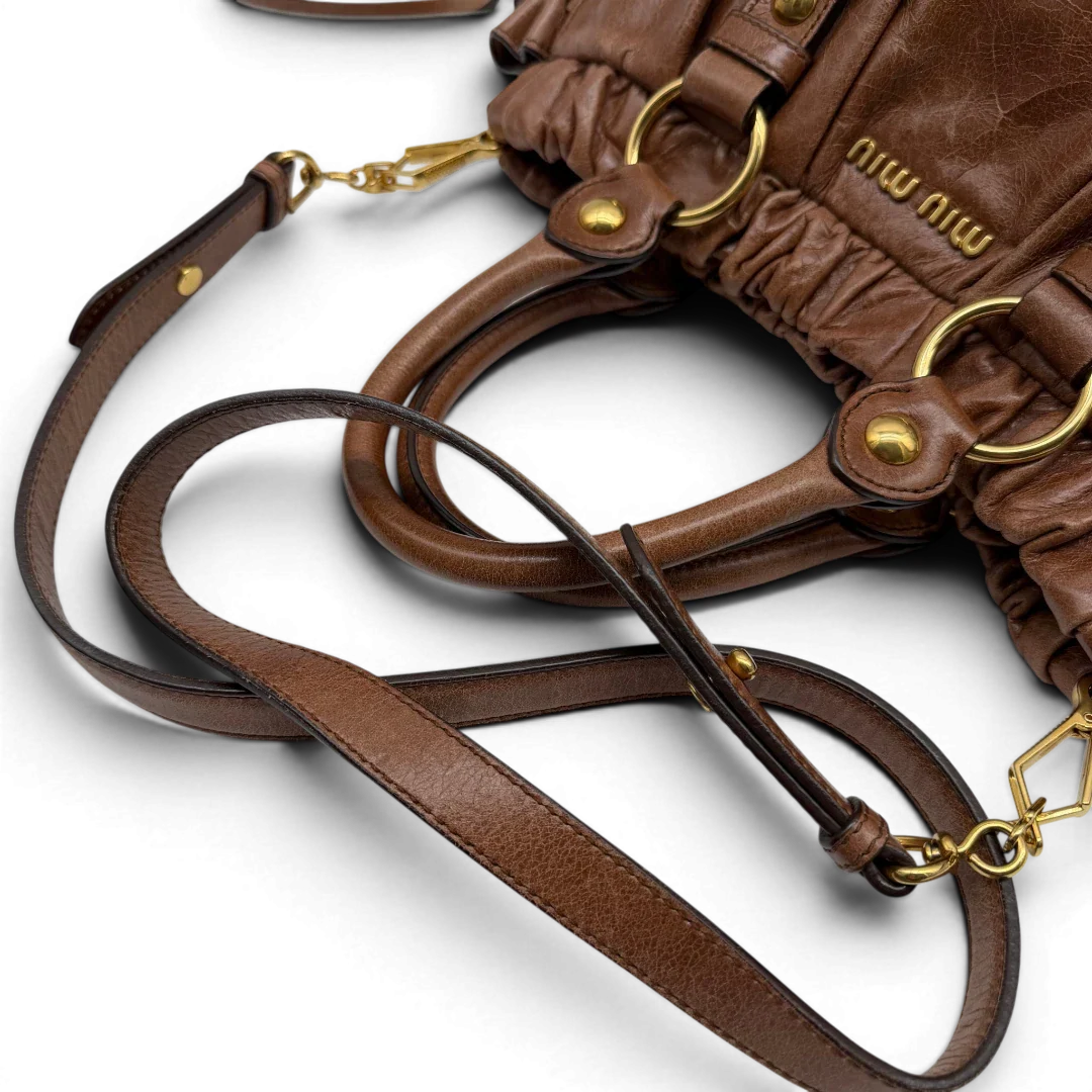 https://cdn.shopify.com/s/files/1/0564/9376/8855/files/Miu_Miu_Handtasche_Vitello_Lux_mit_Umhangegurt_aus_Leder_braun_vintage6502.webp?v=1778682434