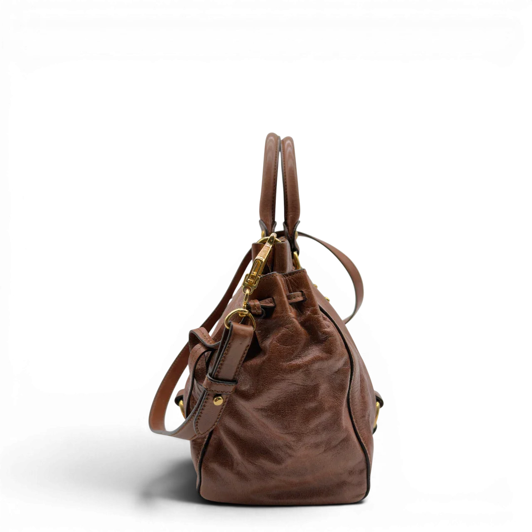 https://cdn.shopify.com/s/files/1/0564/9376/8855/files/Miu_Miu_Handtasche_Vitello_Lux_mit_Umhangegurt_aus_Leder_dunkelbraun_vintage7245.webp?v=1778681726