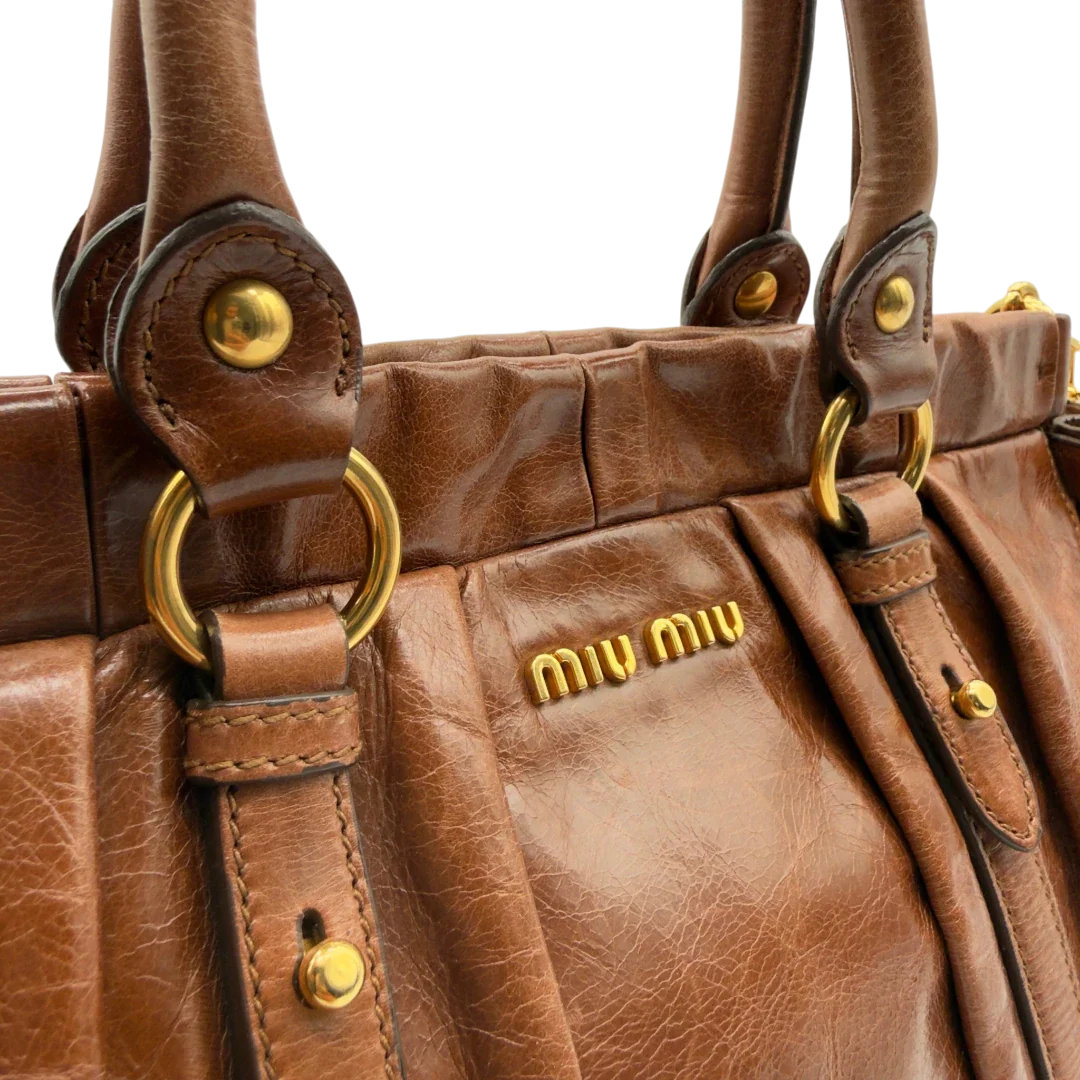 https://cdn.shopify.com/s/files/1/0564/9376/8855/files/Miu_Miu_Handtasche_Vitello_Lux_mit_Umhangegurt_aus_Leder_dunkelbraun_vintage7248.webp?v=1778681729
