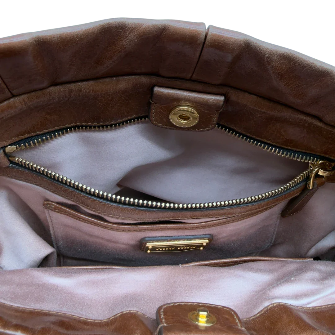 https://cdn.shopify.com/s/files/1/0564/9376/8855/files/Miu_Miu_Handtasche_Vitello_Lux_mit_Umhangegurt_aus_Leder_dunkelbraun_vintage7253.webp?v=1778681727
