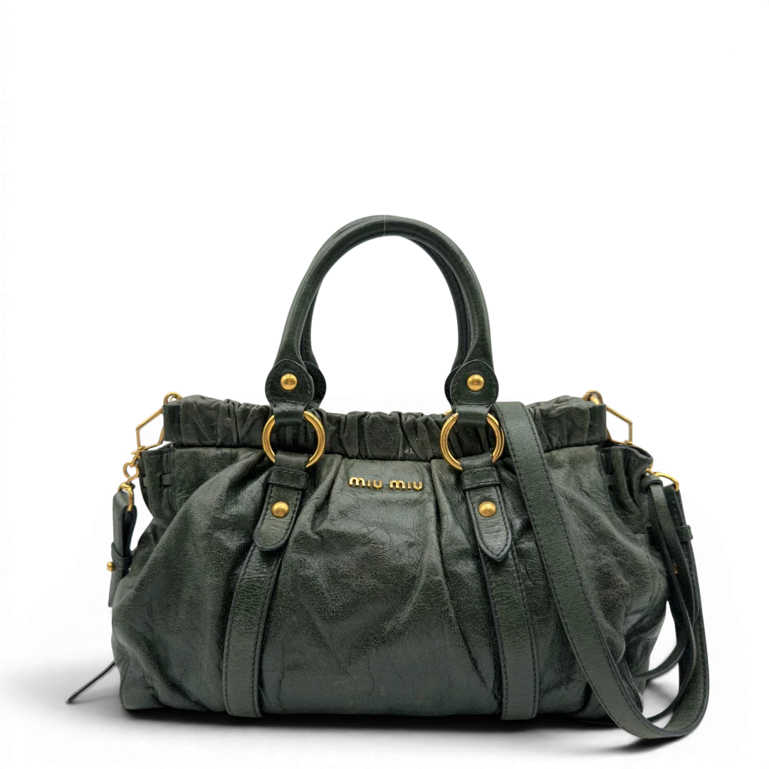 https://cdn.shopify.com/s/files/1/0564/9376/8855/files/Miu_Miu_Handtasche_Vitello_Lux_mit_Umhangegurt_aus_Leder_dunkelgrun_vintage7442.webp?v=1779291830