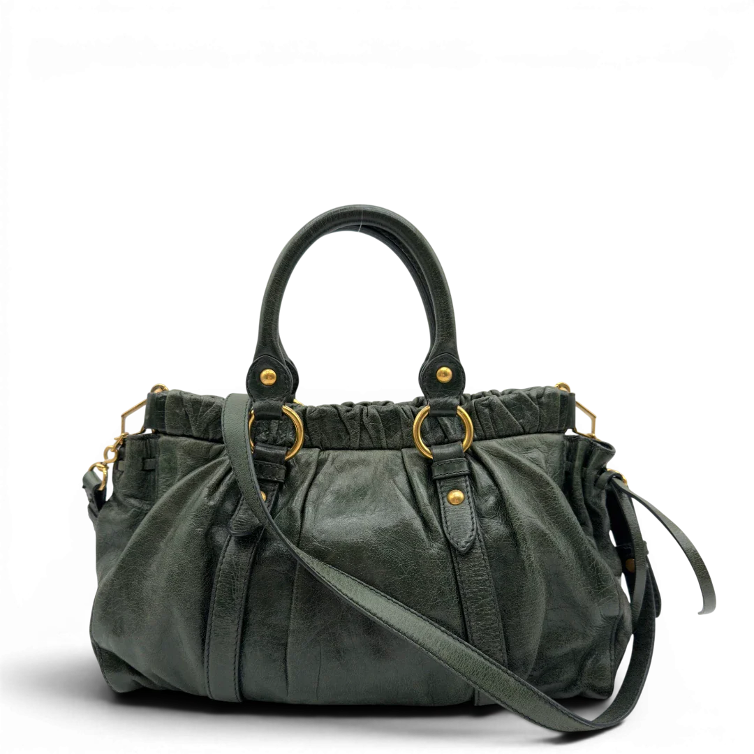 https://cdn.shopify.com/s/files/1/0564/9376/8855/files/Miu_Miu_Handtasche_Vitello_Lux_mit_Umhangegurt_aus_Leder_dunkelgrun_vintage7443.webp?v=1779291830