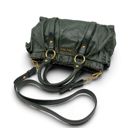 https://cdn.shopify.com/s/files/1/0564/9376/8855/files/Miu_Miu_Handtasche_Vitello_Lux_mit_Umhangegurt_aus_Leder_dunkelgrun_vintage7453.webp?v=1779291831