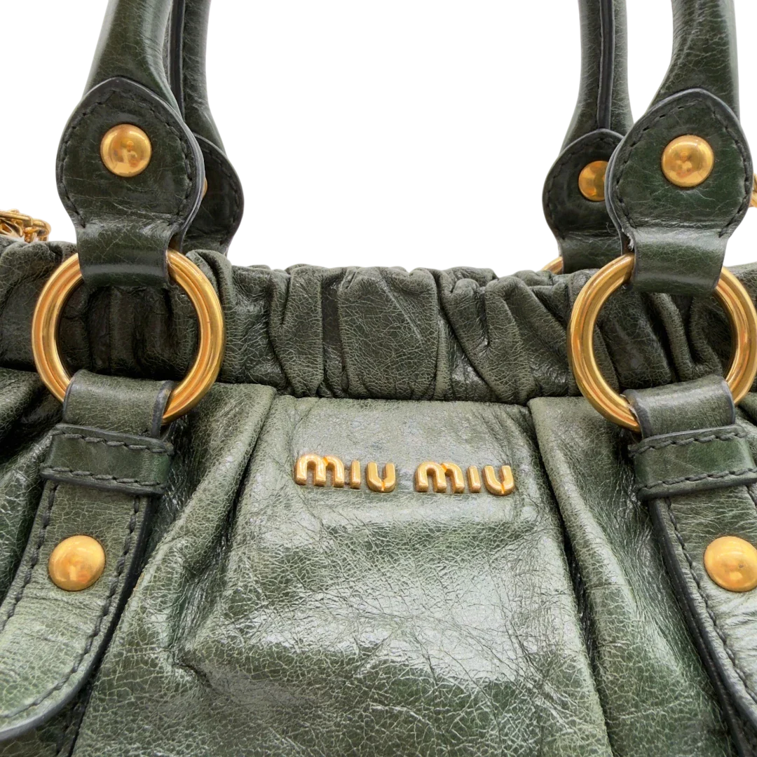 https://cdn.shopify.com/s/files/1/0564/9376/8855/files/Miu_Miu_Handtasche_Vitello_Lux_mit_Umhangegurt_aus_Leder_dunkelgrun_vintage7454.webp?v=1779291831
