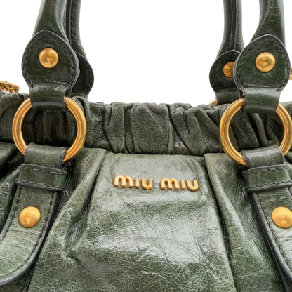 https://cdn.shopify.com/s/files/1/0564/9376/8855/files/Miu_Miu_Handtasche_Vitello_Lux_mit_Umhangegurt_aus_Leder_dunkelgrun_vintage7454.webp?v=1779291831