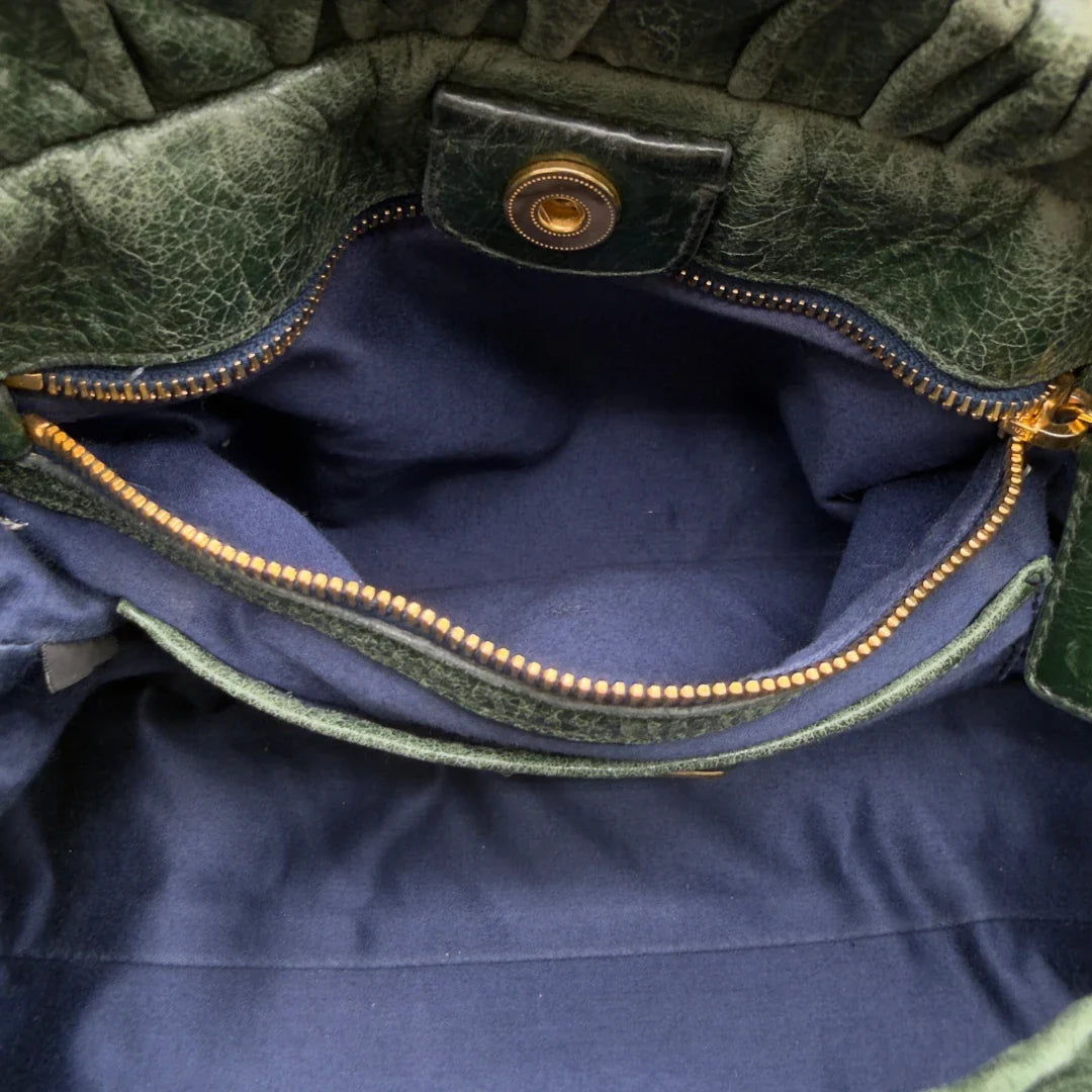 https://cdn.shopify.com/s/files/1/0564/9376/8855/files/Miu_Miu_Handtasche_Vitello_Lux_mit_Umhangegurt_aus_Leder_dunkelgrun_vintage7458.webp?v=1779291831
