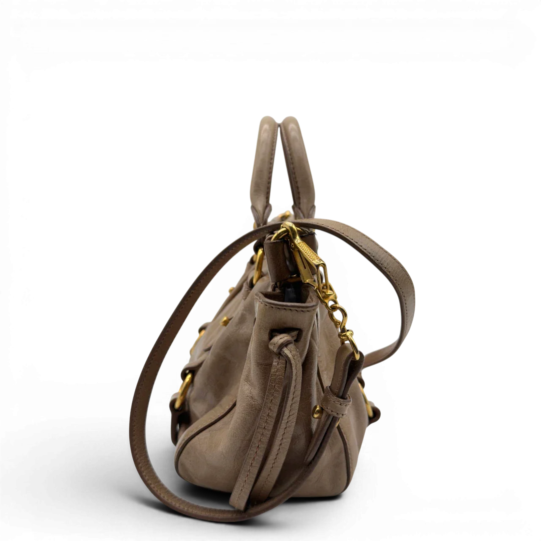 https://cdn.shopify.com/s/files/1/0564/9376/8855/files/Miu_Miu_Handtasche_Vitello_Lux_small_mit_Umhangegurt_aus_Leder_beige_vintage7406.webp?v=1778679864