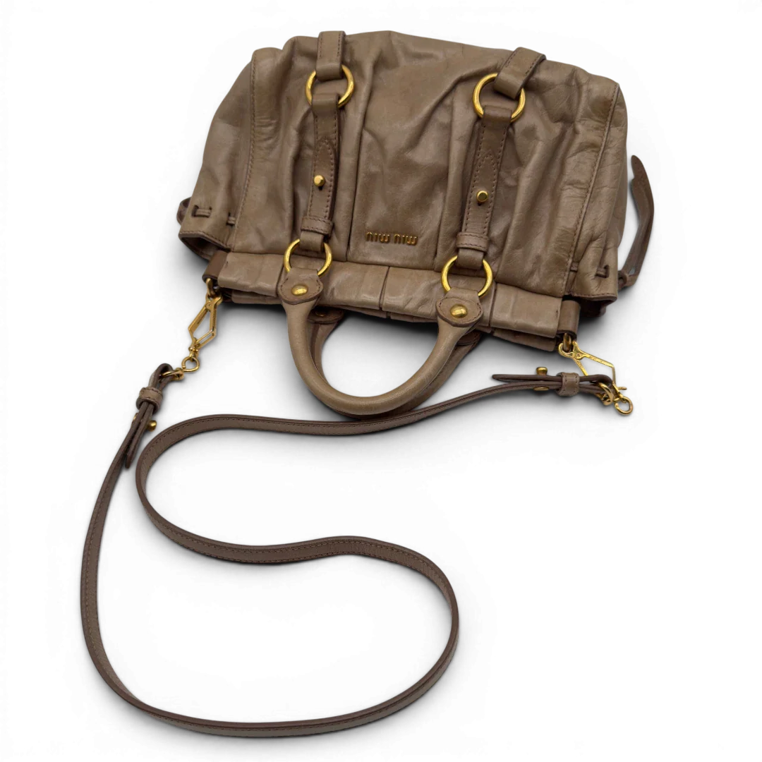 https://cdn.shopify.com/s/files/1/0564/9376/8855/files/Miu_Miu_Handtasche_Vitello_Lux_small_mit_Umhangegurt_aus_Leder_beige_vintage7414.webp?v=1778679864