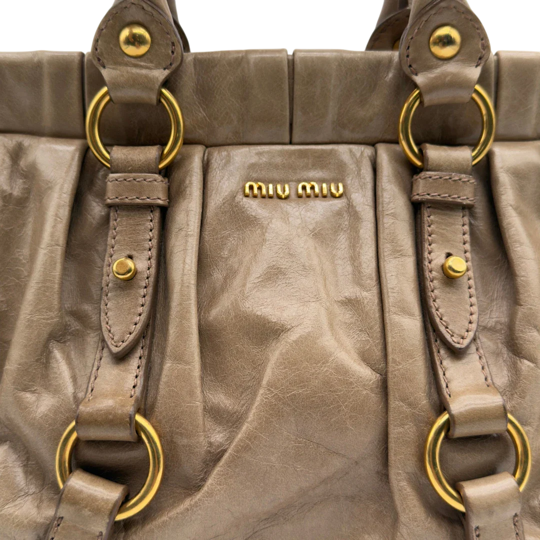 https://cdn.shopify.com/s/files/1/0564/9376/8855/files/Miu_Miu_Handtasche_Vitello_Lux_small_mit_Umhangegurt_aus_Leder_beige_vintage7415.webp?v=1778679864