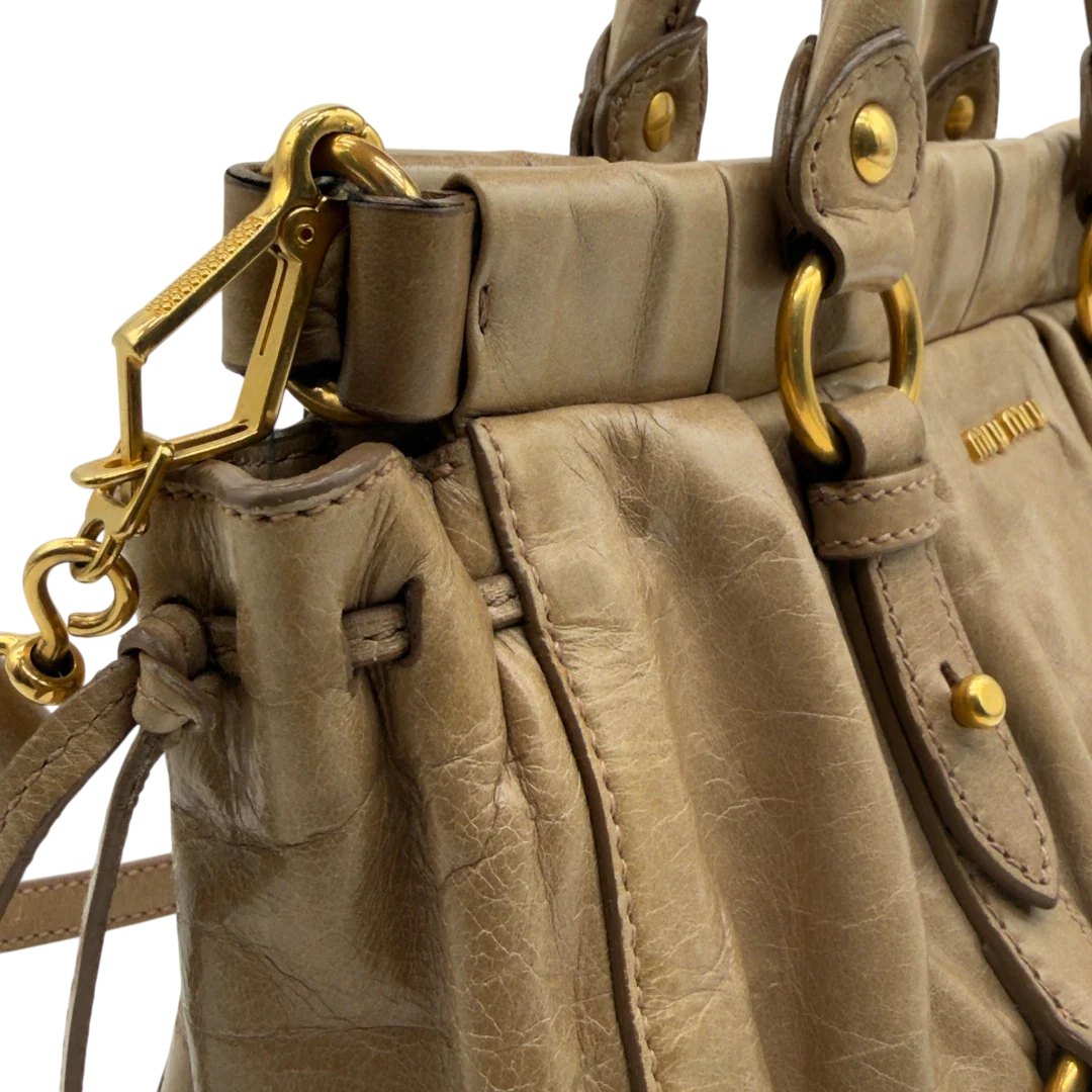 https://cdn.shopify.com/s/files/1/0564/9376/8855/files/Miu_Miu_Handtasche_Vitello_Lux_small_mit_Umhangegurt_aus_Leder_beige_vintage7416.webp?v=1778679864