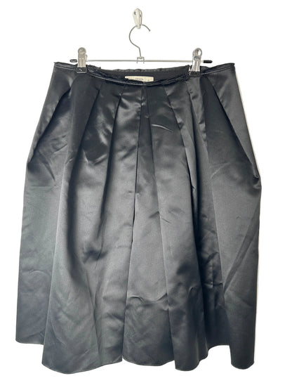 Folded black skirt on a clear hanger against a beige background
