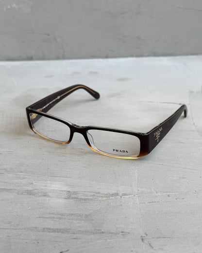 Prada Clear Lens Brown Frame Glasses-on a concrete background