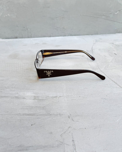 Prada Clear Lens Brown Frame Glasses-on a concrete background