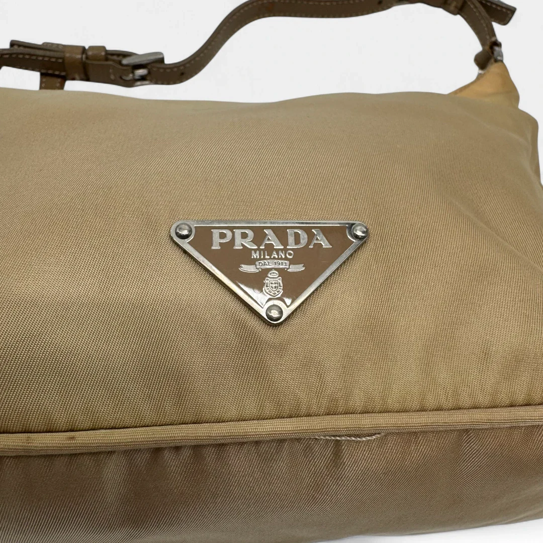 https://cdn.shopify.com/s/files/1/0564/9376/8855/files/Prada_Handtasche_Halbmond_aus_Nylon_beige_second_hand_designer_handbag3650.webp?v=1757671179