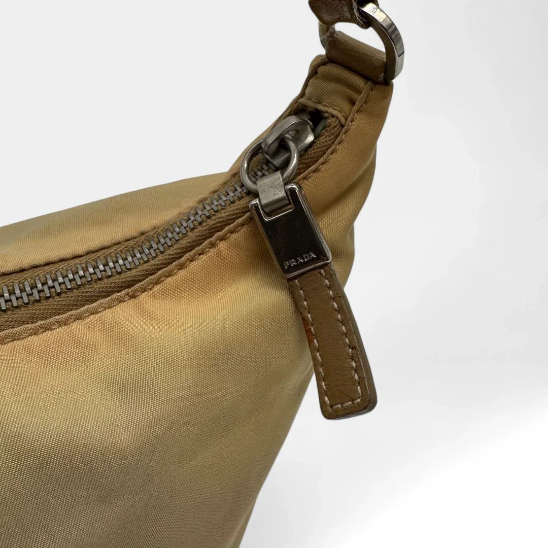 https://cdn.shopify.com/s/files/1/0564/9376/8855/files/Prada_Handtasche_Halbmond_aus_Nylon_beige_second_hand_designer_handbag3651.webp?v=1757671178