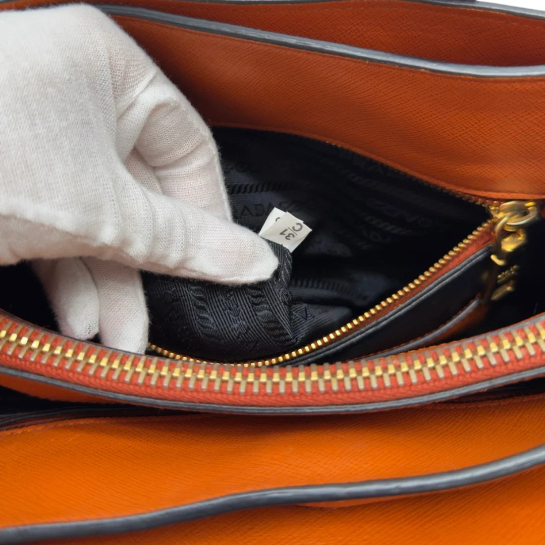 https://cdn.shopify.com/s/files/1/0564/9376/8855/files/Prada_Handtasche_Triple_Pocket_aus_Leder_papaya_orange_26.webp?v=1783516495