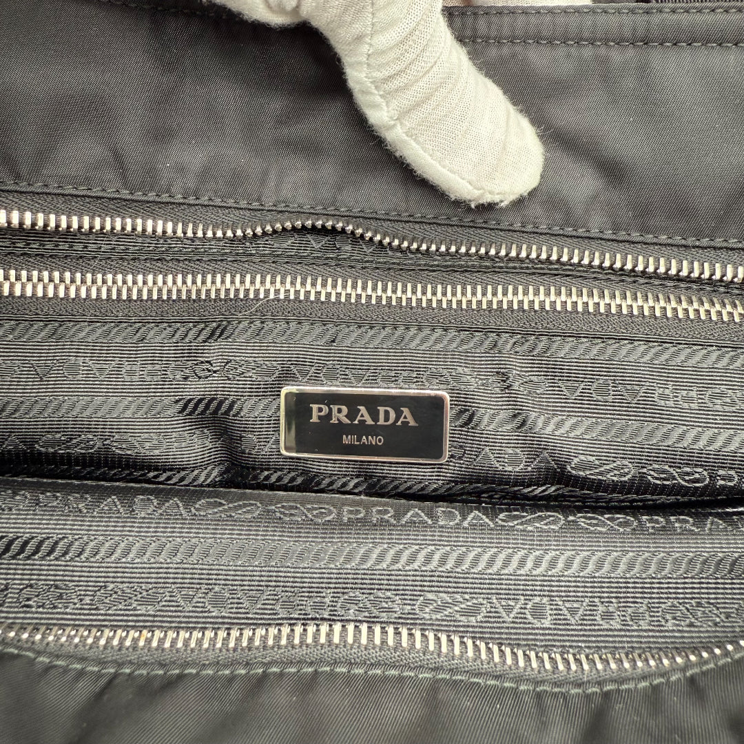 https://cdn.shopify.com/s/files/1/0564/9376/8855/files/Prada_Handtasche___Wickeltasche_aus_Re-Nylon_schwarz_handbag_6138.webp?v=1766106413